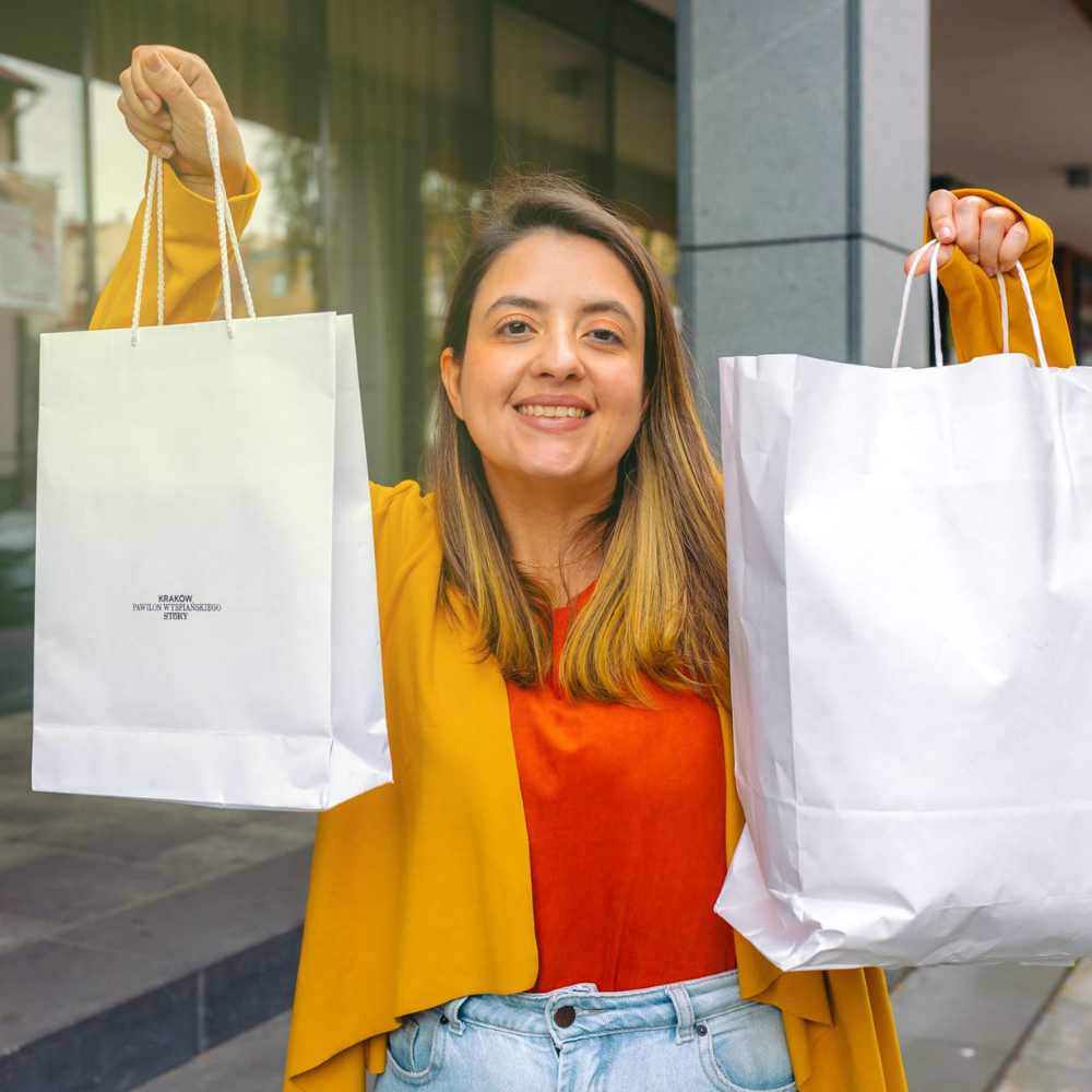 Experiência de compra personalizada: mulher sorri segurando duas sacolas de compra de papel