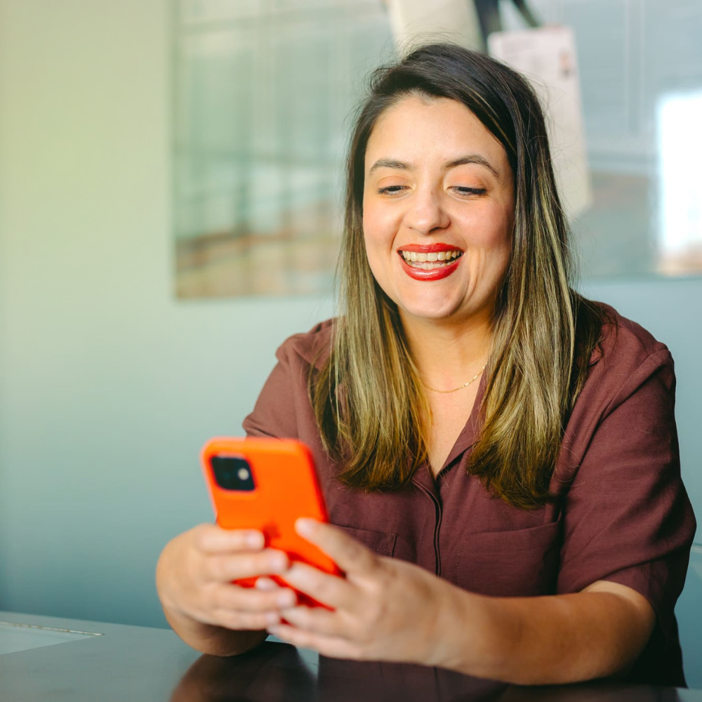 Inbound Commerce: mulher sorri segurando olhando para a tela do celular