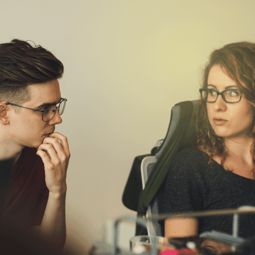 Homem e mulher usam óculos e discutem como aumentar as vendas de lojas virtuais