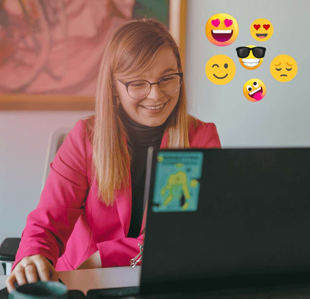 Mulher loira de óculos olha o computador enquanto procura emojis para usar no e-mail